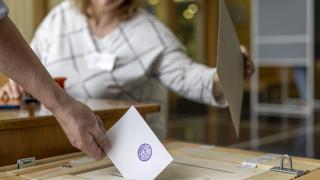 Henkilö laittaa äänestyslapun vaaliuurnaan.