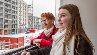 Äiti ja tytär tutustumassa uuteen asuntoonsa ja katsomassa parvekkeelta näkymiä.