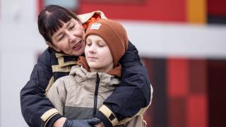 Äidilla on kädet alakoululaisen pojan ympärillä