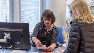 Vantaa-infon työntekijä opastaa asiakasta pöydän ääressä