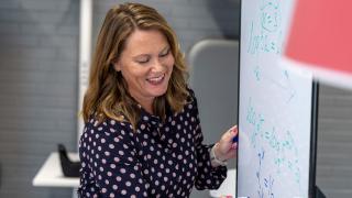 Nainen piirtää taululle.