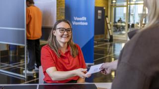 Henkilö ojentaa vaalilipuketta vaalitoimitsijalle. 