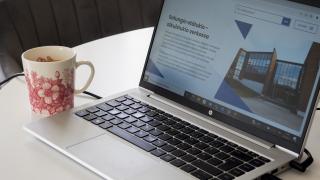 Läppäri ja kahvikuppi pöydällä.