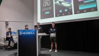 Opiskelijat pitävät esitystä valkokankaan edessä.