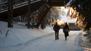 Kaksi kävelijää alittamassa Kuusijärven sisääntuloportin talvisäällä.