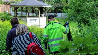 Neonvihreään takkiin pukeutunut Vantaan purotalkkari johdattamassa kahta talkoolaista ojan varteen viherkasviston ympäröimänä. 