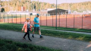 Kaksi aikuista lenkkeilee reippaasti Hakunilan urheilupuistossa.