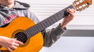 Oppilas soittaa akustista kitaraa.
