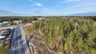 Ilmakuva jossa näkyy Hakunilantietä sekä Vaaralanmäen kalliota ja metsäaluetta sen päällä aurinkoisella ilmalla.