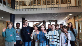 Koululaiset vilkuttavat kaupungintalon aulassa.