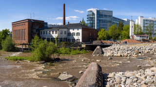 Kulttuuritehdas Vernissa ja palokalustovarasto kuvattuna joen rannalla 2021.