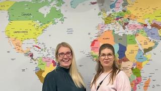 Lehtikuusen koulun rehtorit Elina Kuosmanen ja Tuija Jordan katsovat hymyillen kameraan suuren maailmankartan eteen asettuneina