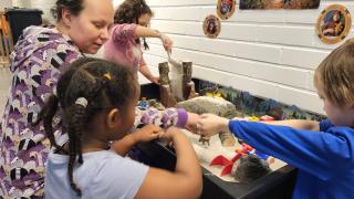 Kehittäjäsosionomi Nina Pohjonen leikkii lasten kanssa dinosauruksilla.