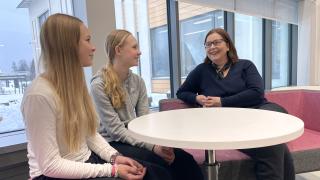 Satu istuu kahden oppilaan kanssa koulun sohvilla.