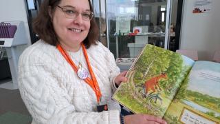 Bibliotekarien visar ett uppslag på Mamma Mu -boken