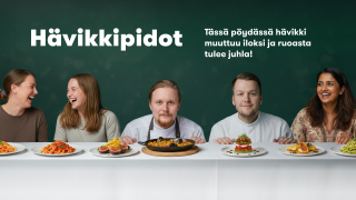 Lauri Kaivoluoto ja Henri Hytönen pitkän pöydän ääressä ja vieressä on iloisia ihmisiä. 