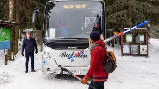 hiihtäjä kävelee hop-on hop-of bussille.