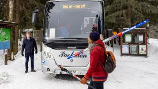 hiihtäjä kävelee hop-on hop-of bussille.