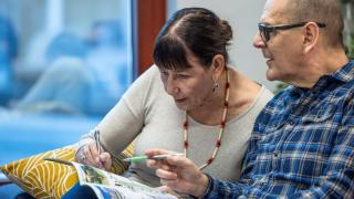 kaksi eläkeläistä selaavat lehteä