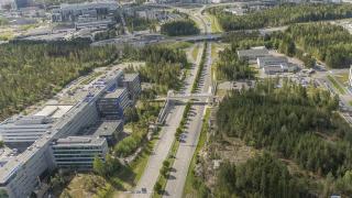 Ilmakuva tiestä, rakennuksista ja metsästä.