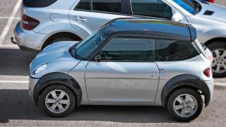 Kaksi harmaata autoa pysäköitynä omalle parkkiruudulle.