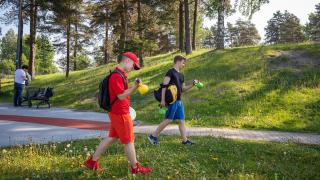 kaksi nuorta kahvakuulat käsissä kävelevät puistossa.