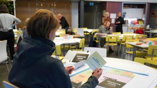 Ihminen istuu pöydän ääressä papereita edessään. 