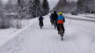 koululaiset pyöräilee kouluun talvella.