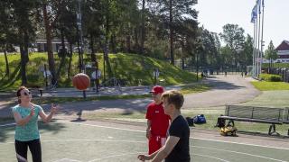 nuoret ihmiset pelaavat koripalloa urheilukentalla.