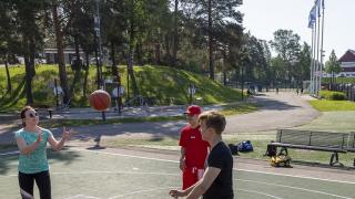 nuoret ihmiset pelaavat koripalloa urheilukentalla.