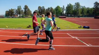 nuoret juoksevat urheilukentällä.