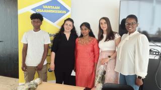 Viisi opiskelijaa seisoo vierekkäin kevätjuhlassa.