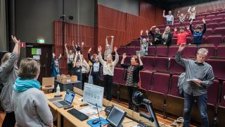 Oppilaita ja aikuisia auditoriossa.