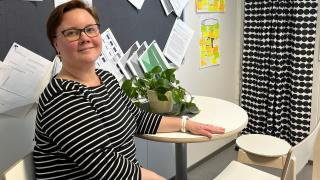 Päiväkodin johtaja Heidi Kivimäki poseeraa pöydän ääressä.