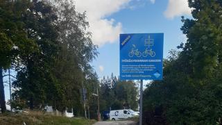 Pyöräilysuunnan ilmaisijasta kertova kyltti pyörätien reunassa.