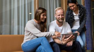 kolme ihmistä katsoo tietokonetta yhdessä.