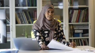 Hijabia käyttävä nainen työpöydän ääressä.