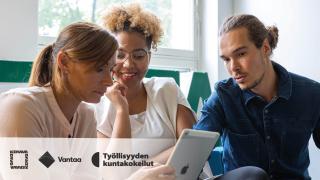 Kuvassa kolme henkilöä katsoo tablettia.