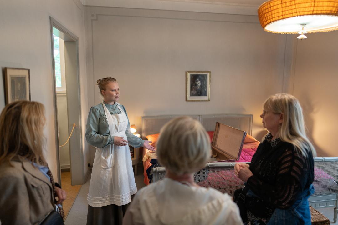 Museo-opas ja yleisöä Håkansbölen kartanon makuuhuoneessa.