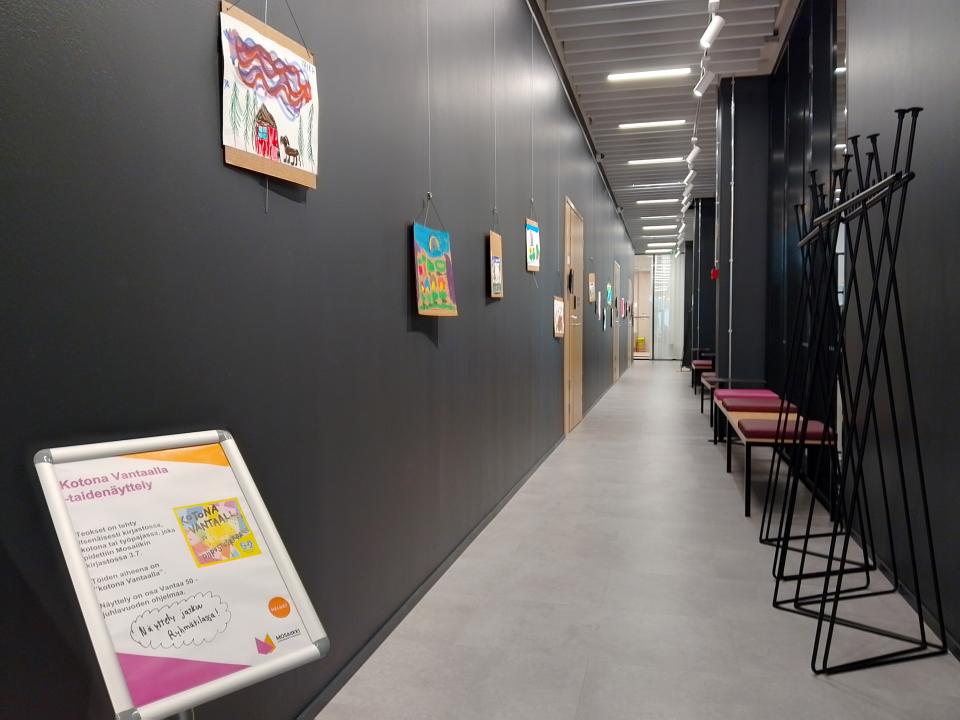 Tummaseinäinen käytävä, jossa seinällä piirrustuksia