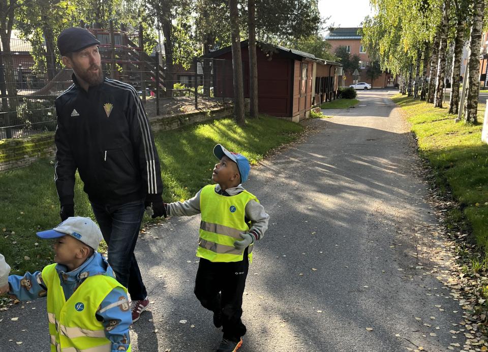 Varhaiskasvatuksen johtaja ja lapsi kävelevät jonossa kohti leikkipaikkaa.