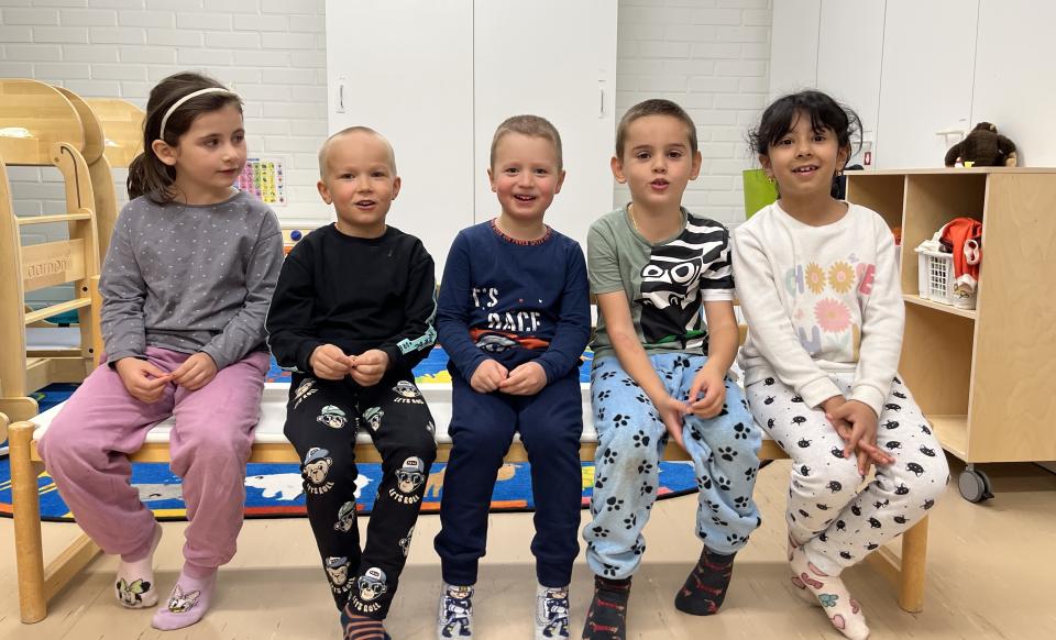 Viisi lasta istuu penkillä päiväkodissa.