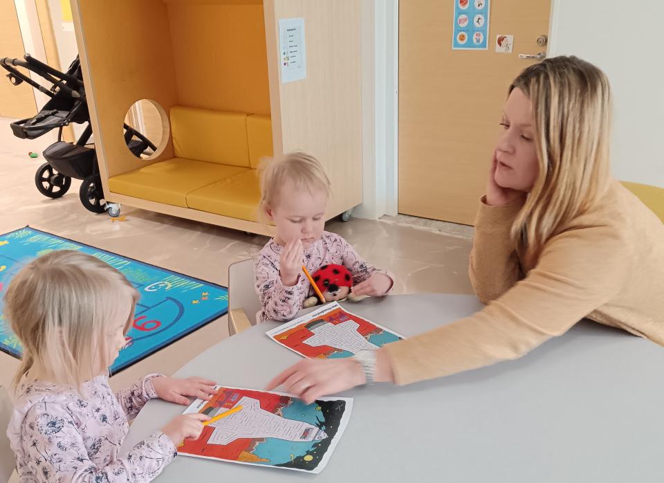 Varhaiskasvatuksen opettaja Katja Torkkola piirtää lasten kanssa. 