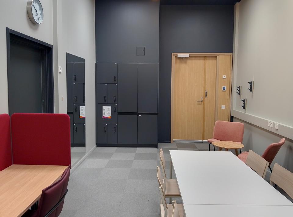 Pienehkö kokoustila, jossa pöytäryhmä. Kuva otettu huoneen perältä ovellepäin. 