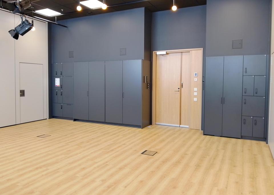 Tyhjätila, jossa vaalea lattia. Tilan perällä tumma seinä, jossa ovi ja mustia kaappeja.