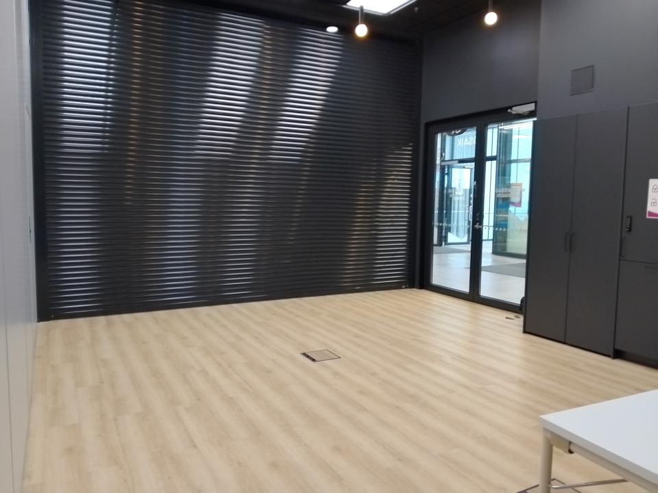 Tyhjätila, jossa vaalea lattia, seiniä kiertää mustat kaapit ja ruloseinä. 