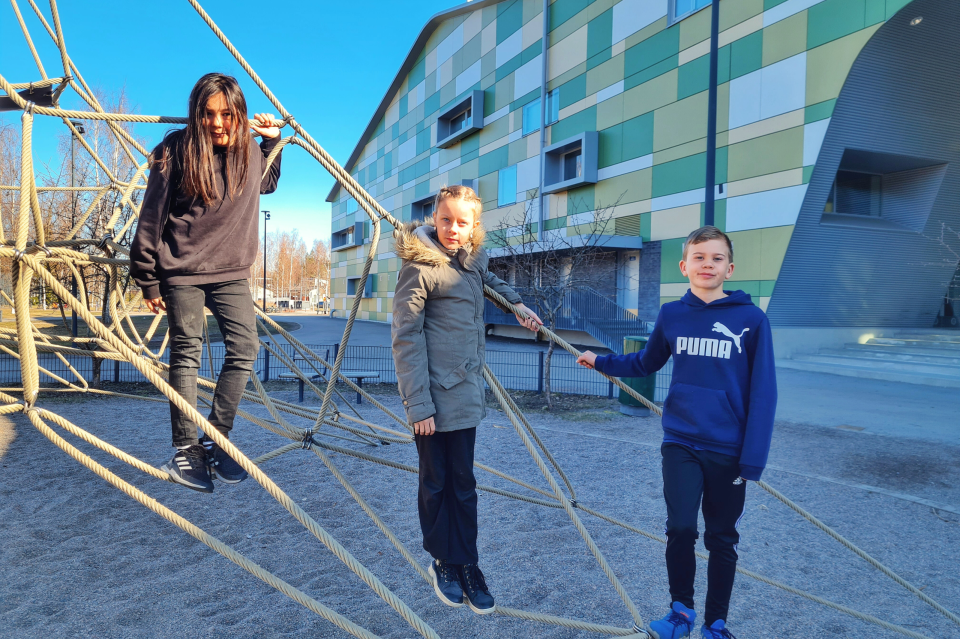 Kanniston koulun oppilaat Diego, Janna ja Lenni kiipesivät kiipeilytelineeseen koulun pihalla.