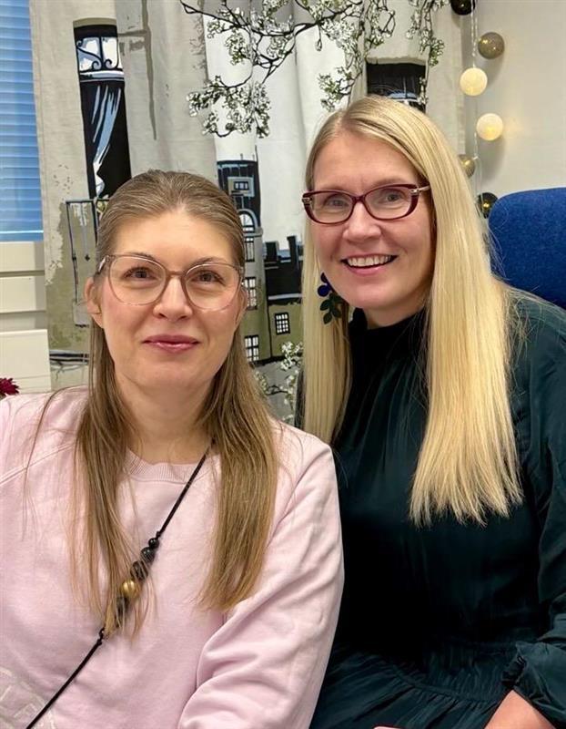 Lehtikuusen koulun rehtorit Elina Kuosmanen ja Tuija Jordan hymyilevät luokkahuoneessa kameralle.