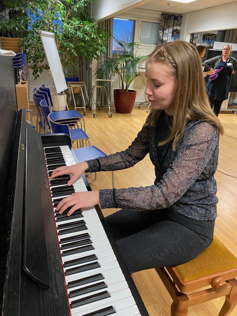 nainen soittamassa tummaa, puista pianoa