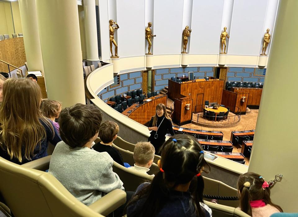 Eskarilaiset kuuntelevat Eduskuntatalon lehtereillä oppaan kertomuksia.
